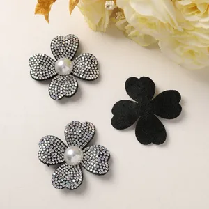 Close-up detail of sparkling rhinestone and pearl four-petal flower DIY craft accessories.