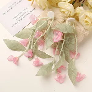 Close-up detail of forest lily of the valley earrings with green lace and pink flowers.