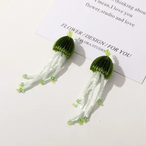 Beaded jellyfish earrings detail close up green and white handmade floral tassel drop design.