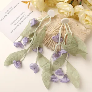 Detailed close-up of fairy-like green leaf and purple bellflower tassel earrings, forest style.