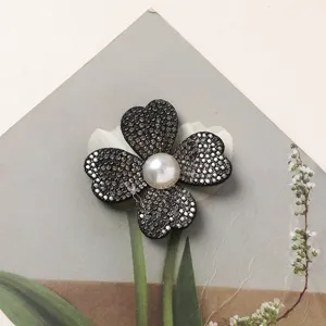 Close-up detail of rhinestone four-petal flower DIY accessory with pearl center.