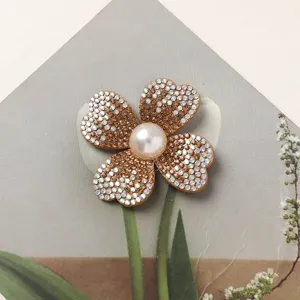 Close-up of sparkling rhinestone four-petal flower accessory with center pearl for DIY crafting.