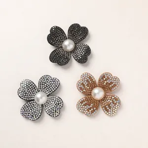 Detail view of sparkly rhinestone four-petal flower DIY accessories with central pearl beads.