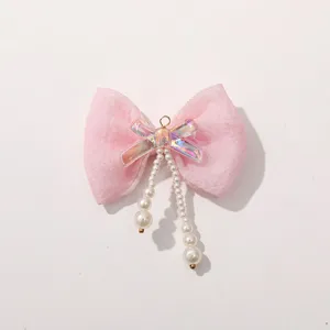 Close-up detail of the pink mesh bow with iridescent center and hanging pearl strings for hair accessory.