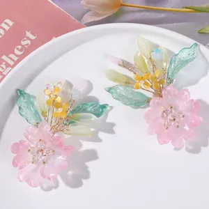 Close-up detail of handmade beaded pink flower hair clip with green leaves and delicate wire work.