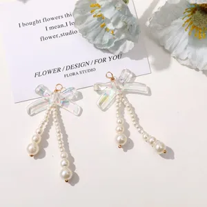 Detailed view of iridescent bow earrings with hanging pearl strands, handmade jewelry.