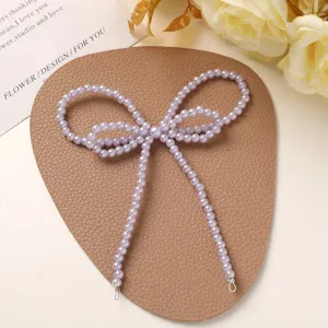 Close-up detail of the elegant purple imitation pearl bow accessory, exquisite craftsmanship.
