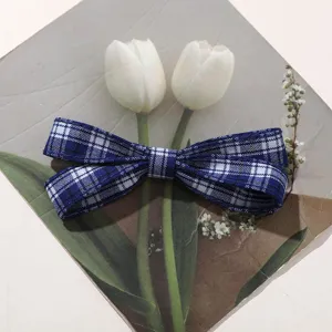Detailed shot of the blue and white plaid fabric bow hair clip featuring a classic design.