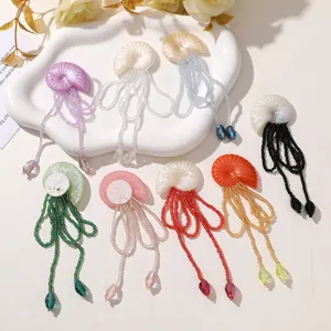 Detailansicht von bunten Muschel Quallen Perlenquasten Broschen und DIY Haaraccessoires.