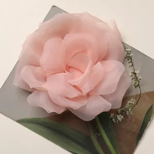 Primo piano dettagliato di un accessorio floreale a rosa in morbido chiffon rosa tenue.