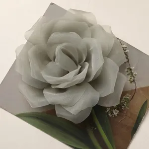 Dettaglio fiore di rosa in chiffon grigio, squisito accessorio in tessuto multistrato.