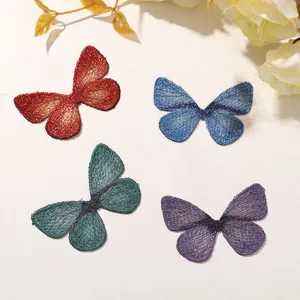 Gros plan de patchs de papillons brodes de paillettes colorees pour vetements DIY.