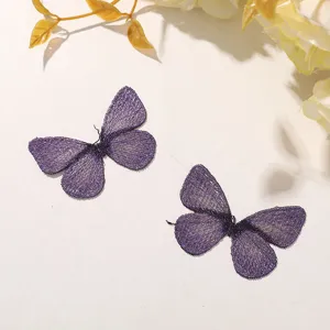 Gros plan détaillé de patchs de papillons brodés violet scintillant avec des fils métalliques.
