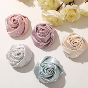 Detailed close-up view of colorful fabric rose flower buds decorated with pearls for DIY crafts.