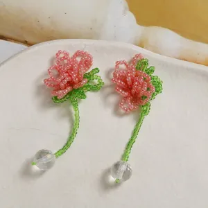 Handmade beaded flower earrings detail view, pink petals with crystal ball pendant.