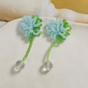 Handmade beaded flower earrings detail view featuring crystal ball pendant and green bead stem.