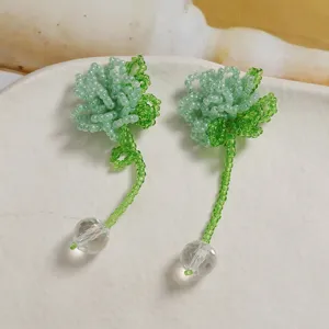 Detailed close-up view of handmade green beaded flower earrings with crystal ball dangles.