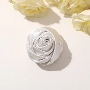 White fabric rose flower bud detail close up with small pearl embellishments for DIY craft.