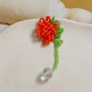 Handmade beaded flower hair accessory detail view, featuring vibrant orange petals and crystal.