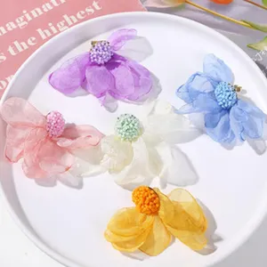 Detailed view of handmade mesh flower hair clips with beaded centers in vibrant colors.