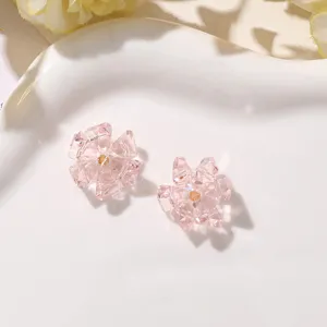 Detailed close-up of pink crystal flower DIY stud earrings and accessories on a white plate.