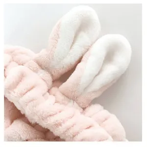 Gros plan détaillé du bandeau oreilles de lapin en peluche rose douce, texture polaire.