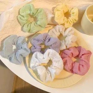 Detailed view of multiple pastel scrunchies set featuring soft fabric and varied colors.