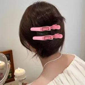 Close-up view of pink hair sectioning clips worn on hair for root volume and styling detail.
