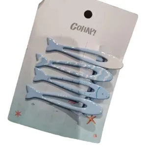 Set di quattro fermagli per capelli a forma di pesce blu su carta bianca decorata carina.