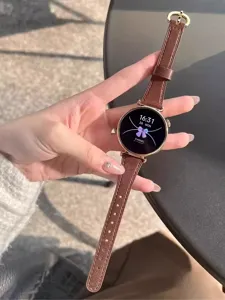 Primo piano del cinturino per orologio sottile in pelle marrone con fibbia oro, finitura liscia.