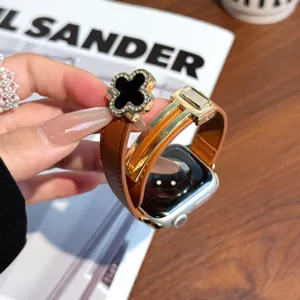 Detail view of brown leather Apple Watch strap featuring elegant clover charm and magnetic clasp.