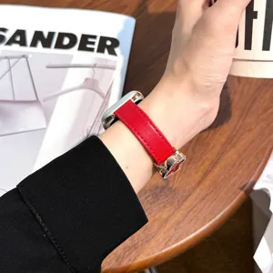 Red leather watch strap detail view, elegant clover magnetic buckle, premium wristband.