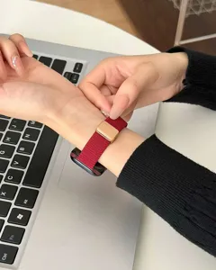 Primo piano dettagliato di un cinturino per orologio in nylon rosso con fibbia magnetica dorata.