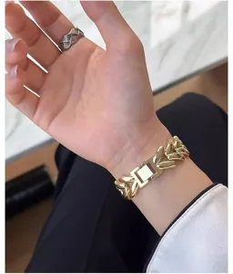 Closeup of a luxury gold metal heart link chain watch strap worn elegantly on a slender wrist.