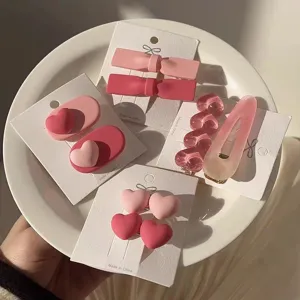 Détail de l'ensemble de pinces à cheveux rose doux avec cœurs et nœuds sur carte.