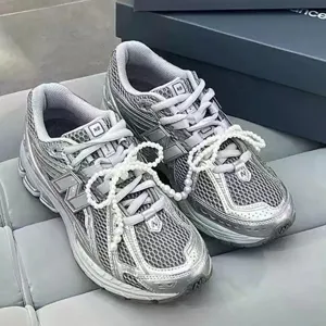 Sneakers rétro argento metallizzato con eleganti decorazioni di lacci a fiocco di perle.
