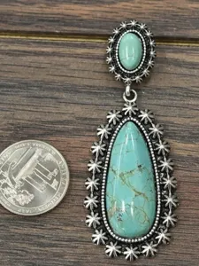Close-up detail of vintage silver teardrop turquoise earring next to a coin indicator
