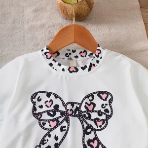 Close-up of girl's white top featuring a stylish pink leopard print bow detail