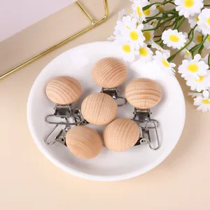 Nahaufnahme von Schnullerkettenclips aus Buchenholz auf einem weißen Teller mit Blumen