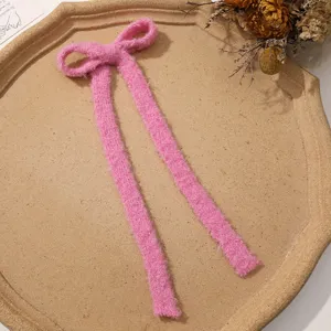 Cute pink fuzzy plush ribbon bow hair clip accessory, soft winter style detailed view.