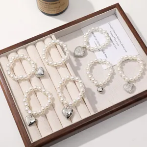 Handmade pearl bead bracelets with silver heart pendants, elegant jewelry accessory set.