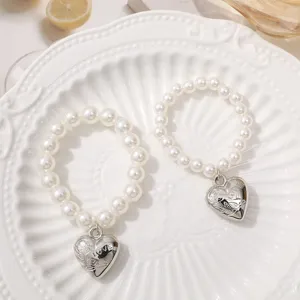White faux pearl beaded bracelets with silver heart pendants, fashionable Y2K style jewelry.