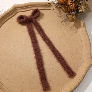Fluffy brown long ribbon bow hair clip detail, cozy plush autumn hair accessory.