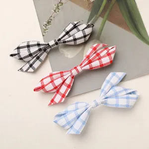 Detailed shot of plaid fabric bow hair clips, featuring black, red and blue checkered patterns.