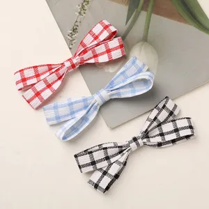 Detailed close-up of handmade fabric plaid bow hair clips in red, blue, and black grid designs.
