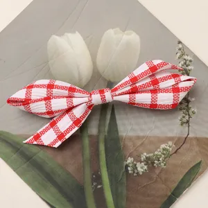 Red and white checkered fabric bow hair accessory detail shot, cute style hair clip.