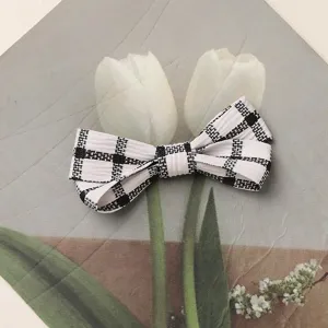 Black and white plaid fabric bow hair accessory detail shot, elegant hairpin for daily wear.