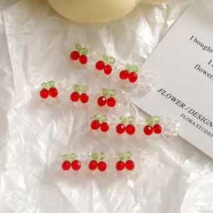 Détail d'une barrette à cheveux perles cerise avec des perles de cristal rouges et vertes scintillantes.