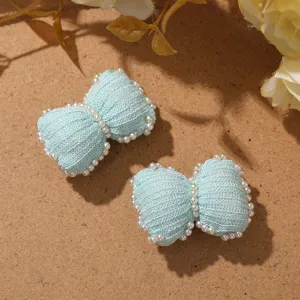 Close-up detail shot of light blue knitted pearl bows, perfect for DIY accessories.
