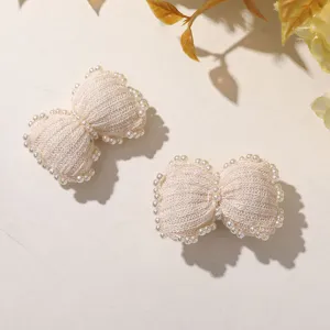 Cream knitted pearl bow detail shot, delicate handmade texture for sweet hair accessory.